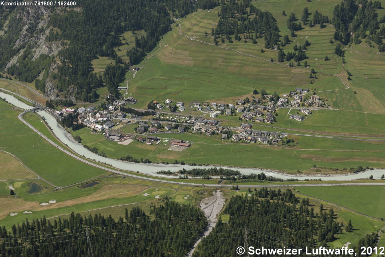 Aue Suottarivas (Position: 2'791'786.02, 1'162'461.12). Blick nordwärts nach Madulain. Dorfteil rechts Mitte: Spih; Dorfteil links: Som Vih. Renaturierte Aue in der Bildmitte. Geschiebe (unterer Bildrand) aus dem Val Greva.